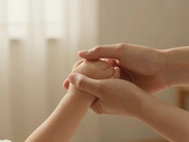 A close-up of a parent's hand gently holding a child's hand, soft warm morning light, beige linen background, shallow depth of field, warm editorial style