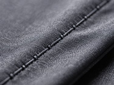 Macro close-up of double-needle stitching on technical activewear fabric under high-contrast directional studio light, showing precise thread alignment.