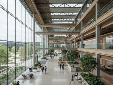 Wide shot of a modern corporate campus atrium with architectural details and natural light, cool tones, 35mm, high-end commercial real estate aesthetic.
