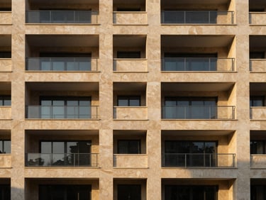 Modern residential compound facade showing warm sand-colored stone and minimalist balconies, golden hour shadows