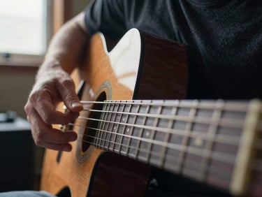 Extreme close-up of a musician's hands on steel guitar strings in a dimly lit studio, natural side light from a single window, no face visible, documentary framing