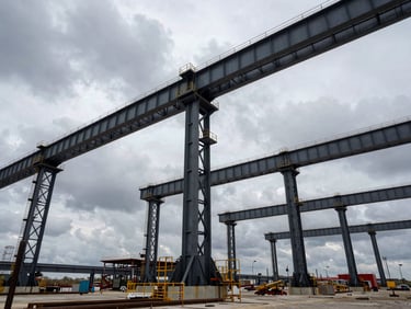 Low-angle wide shot of a massive industrial construction site with steel arches rising against an overcast dramatic sky, structural engineering, 35mm