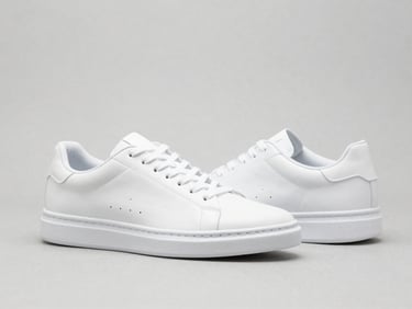Clean studio shot of minimalist white sneakers on a neutral background, bright even light, crisp focus, high-key, 50mm
