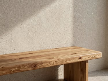 Close-up of a custom oak bench resting against a textured travertine wall in soft morning light