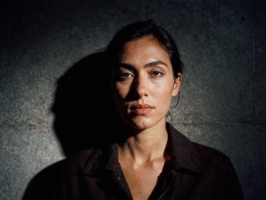 Close-up portrait of a female architect in dark clothing, low-key lighting, cast concrete background with sharp shadows, high contrast, 35mm film