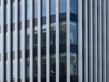 Crisp architectural photography of a modern minimalist corporate building facade with clean lines and reflective glass under cool daylight.