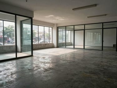 Empty commercial office floor with glass partitions and polished concrete, daylight-balanced north-facing light, Vadodara street view through windows, no people