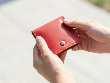 Close-up of hands holding finished custom leather goods, crisp focus, natural daylight