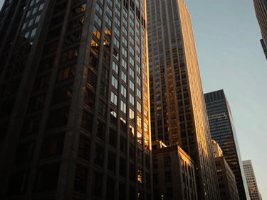 Sleek low-angle shot of Manhattan skyscrapers reflecting golden hour sunlight, deep obsidian shadows.