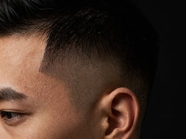 Macro close-up of a flawless high-contrast skin fade on a client, dramatic side-lighting, deep clean shadows, rich obsidian tones, 35mm