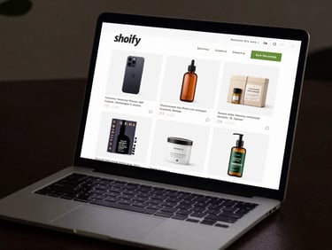 Close-up of a Shopify storefront on a laptop screen, product grid visible, clean studio lighting, dark desk surface