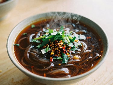 Macro shot of a dark, rich boat noodle broth in a small ceramic bowl, fresh herbs and chili flakes on top, steam rising, plastic table background, raw editorial travel photography.