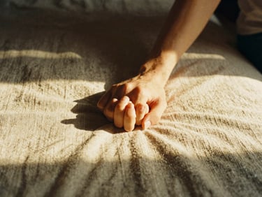 An intimate detail of a couple holding hands on a woven linen sheet, soft shadows, warm golden hour light, 35mm film.