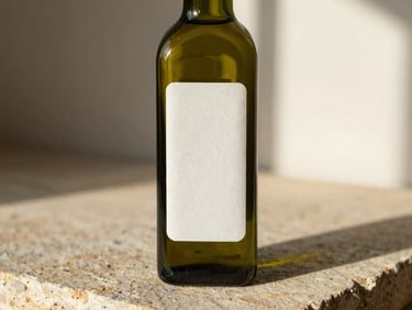 Minimalist olive oil glass bottle with a textured paper label on a rustic stone surface, warm afternoon light, shallow depth of field