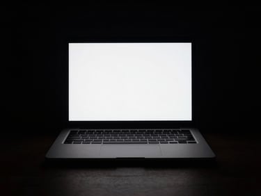 Dark workspace setup with a single laptop screen glowing in the dark, high-contrast chiaroscuro, sharp light-and-shadow geometry