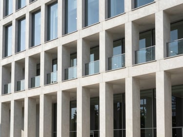 Bright editorial photography of a sunlit modern office building facade with clean architectural lines, morning sun, 35mm