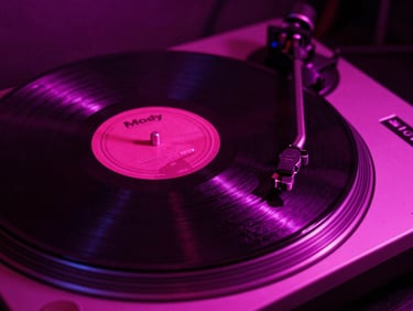 Moody close-up of a vinyl record spinning on a turntable under neon magenta lighting