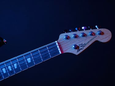 Intimate macro shot of an electric guitar neck under a moody blue studio glow, 35mm lens