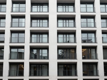 Geometric medium shot of a clean, modern apartment facade in South East London, architectural details, overcast daylight, 35mm.