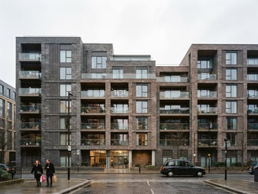 Wide architectural exterior shot of a modern London residential brick building, crisp overcast daylight, desaturated cool tones with subtle warm highlights, sharp focus, 35mm photography.