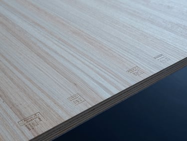 Close-up of structural plywood sheet showing natural wood grain texture and stamped Australian standard certification codes, overcast daylight