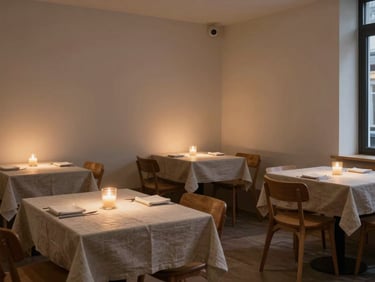 Wide environmental shot of a small independent restaurant interior at dusk, warm candlelight on linen-covered tables, no diners, minimal Scandinavian aesthetic, natural textures, calm atmosphere