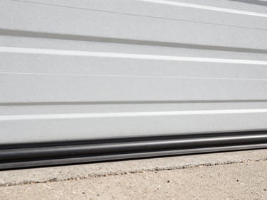 Close-up of a new weather seal being installed along the bottom of a garage door, showing a tight fit.
