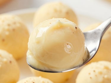 Macro close-up of a creamy brigadeiro on a spoon, showing the rich smooth texture, warm natural light
