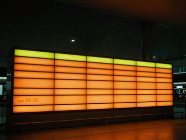 Wide environmental shot of a premium glowing digital airport lightbox in a sleek modern terminal, high-contrast orange lighting