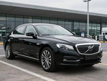 A spotless executive black sedan parked outside a modern UK airport terminal, overcast daylight reflecting off the polished paint
