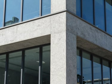 Architectural detail of a modern concrete and glass office workspace, bright natural daylight, cool blue tones, sharp focus