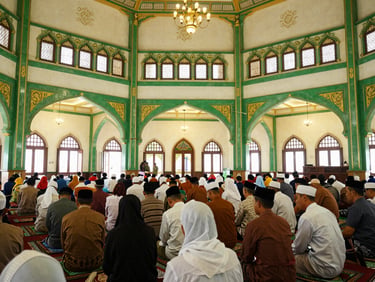 Interior wide shot of a traditional Minangkabau mosque (Masjid Raya) during a community gathering, warm indoor lighting, editorial documentary photography