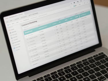 Close-up overhead shot of a laptop screen showing a compliance monitoring dashboard with flagged transaction rows and audit trail columns, cool even office lighting, no people, clean desk surface visible at edges