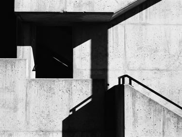 High-contrast black and white architectural detail, sharp geometric shadows on concrete, minimalist composition, 35mm film grain