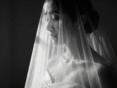 Extreme close-up of a bridal veil caught in sharp, directional window light, deep shadows, high-contrast black and white, 35mm film grain