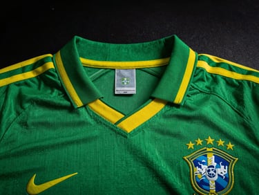 Close-up of a classic green and yellow Brazilian football shirt collar, detailed embroidery of the crest, dramatic studio lighting, dark moody background, high contrast, 50mm lens
