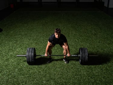 Wide panoramic shot, moody gym lighting, player performing heavy hex bar deadlifts, intense focus.