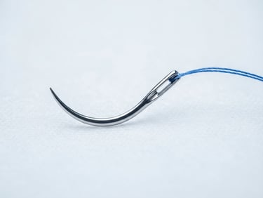 Macro shot of a surgical suture needle under crisp clinical lighting, sterile white background.