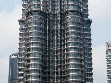 Straight-on architectural exterior of Pavilion Square tower, clean daylight, glass facade geometry, urban KL skyline context in background, precise angles emphasising structural clarity and material quality
