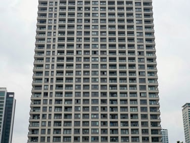 Wide architectural exterior of Orian KL residential tower, clean overcast daylight, straight-on facade revealing urban geometry and floor-plate scale, KL mid-city context visible in background