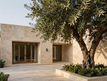 Architectural wide shot of a minimalist travertine villa courtyard in Dubai, featuring a mature olive tree and lush green foliage under warm diffused afternoon sunlight.
