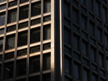 Extreme close-up of a modern steel-and-glass skyscraper structural joint, dramatic sharp shadows, high-contrast architectural lighting