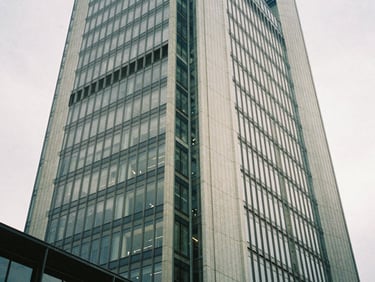 Architectural detail of a modern skyscraper in Frankfurt, low-angle shot, soft diffused daylight, steel and glass textures.