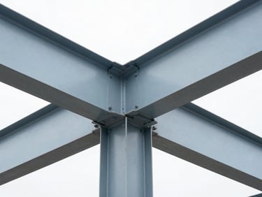 Close-up architectural photograph of heavy steel girders and structural connections, bright overcast daylight, desaturated steel tones.