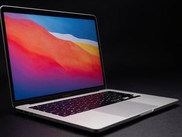 Angled shot of an open MacBook Pro showing a vibrant retina display, sleek aluminum body, dark low-key studio lighting.