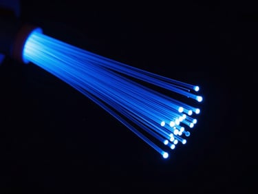 Macro shot of glowing glass fiber optic cables bundle, high contrast studio lighting, deep blue neon accents, dark background.