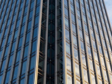 Dramatic close-up of structural glass joints on a commercial skyscraper facade, reflecting the blue sky, silver-blue metallic mullions, millimeter precision alignment
