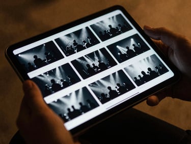 A hand scrolling through a clean, modern photo gallery on a tablet, displaying artistic black and white concert photos, moody backstage lighting, deep blue and warm gold tones, cinematic 35mm film grain.