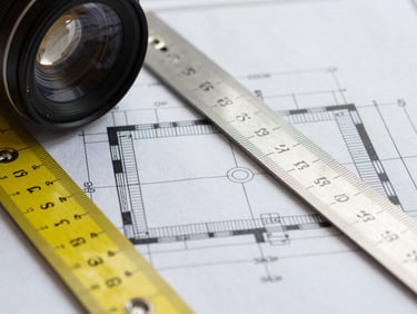 Macro flat-lay of architectural blueprint detailing Reflected Ceiling Plans, with a precision metal scale ruler and technical markup in yellow.