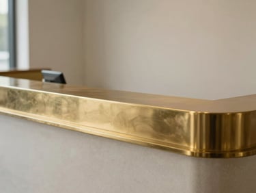 Minimalist architectural detail of a high-end medical reception desk, warm brass accents, clean lines, diffused daylight.